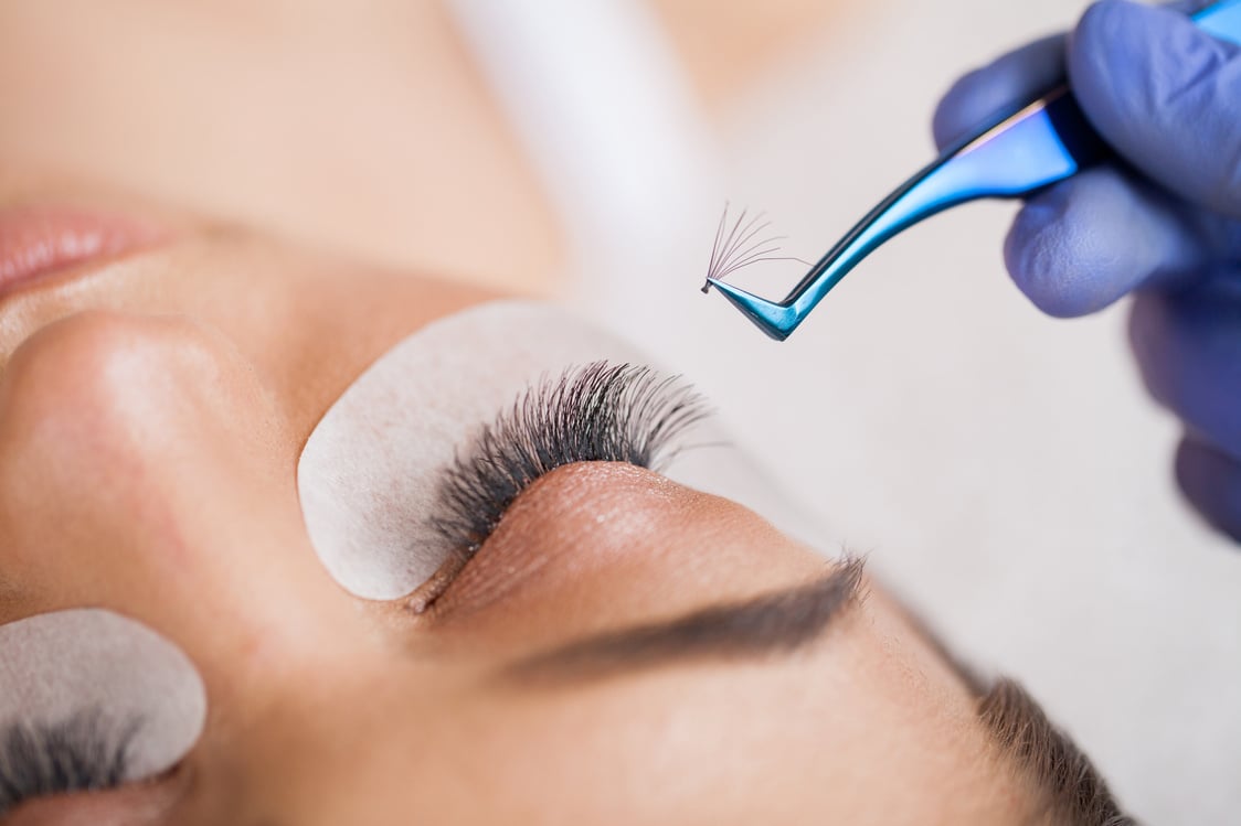 Eyelashes Extensions. Fake Eyelashes. Eyelash Extension Procedure. Professional Stylist Lengthening Female Lashes. Master and a Client in a Beauty Salon